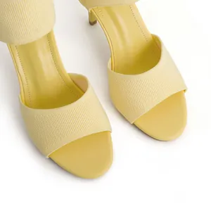 Close-up detail of stylish yellow knit fabric stiletto sandals featuring a round toe design