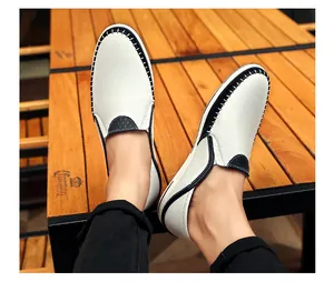 Gedetailleerd overzicht van witte leren loafers met zwarte handgestikte details aan de voeten