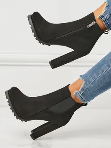 Detailed side view of black suede chunky heel ankle boots featuring a rugged lug sole