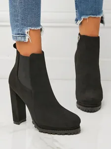 Close-up of stylish black suede Chelsea boots with high block heel and platform lug sole