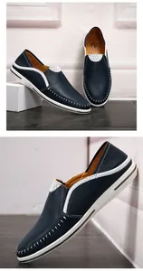 Detail van handgestikte marineblauwe leren loafers met witte contraststiksels en zool