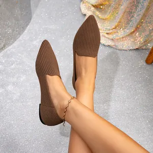 Pointed-toe brown knitted flat shoes worn on a glitter background with an anklet