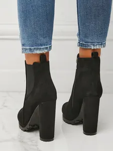Close-up rear view of black suede platform ankle boots with chunky high heels for women.