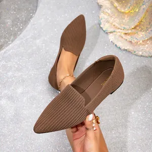 Macro detail of brown pointed-toe fly-knit flat shoes presented on shimmering silver fabric