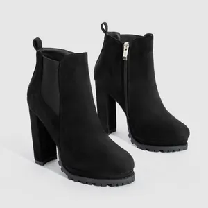 Macro detail of black suede ankle boots with chunky high heels and metallic side zipper