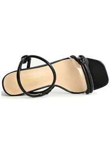Detailed view of black strappy sandals with clear PVC band and square toe design