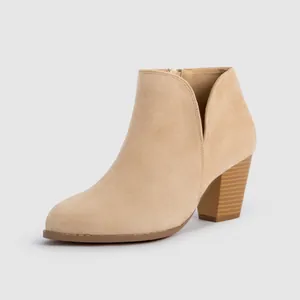 Close-up detail of beige suede ankle boot featuring a chunky heel and side V-cutout design