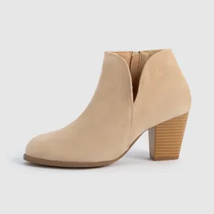 Detail view of beige suede ankle boots with chunky wood-grain heel and side zipper