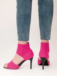 Detail view of hot pink fly-knit stiletto high heel sandals on a model's feet