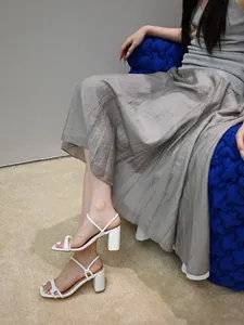 Elegant white square toe block heel sandals with thin straps shown in a lifestyle view