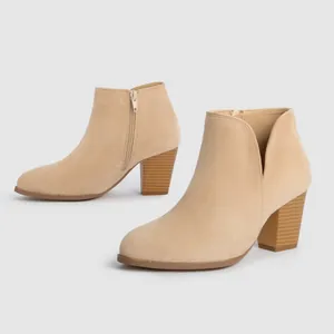 Detail view of beige faux suede ankle boots featuring side zipper and chunky heels