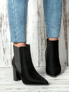 Detail of black suede pointed-toe ankle boots featuring elegant thick block heels