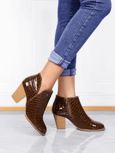Close-up of stylish brown crocodile pattern ankle boots with chunky heel and zipper