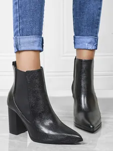 Close-up of black pointed toe ankle boots with snake-skin texture and block heels