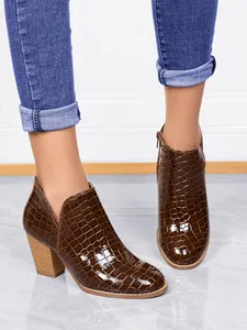 Detailed macro view of brown crocodile-patterned chunky heel ankle boots for women
