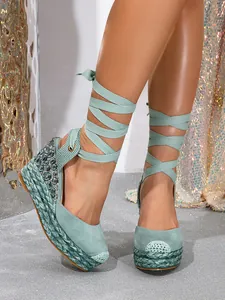 Detailed close-up of green suede platform sandals with rhinestones and ribbons