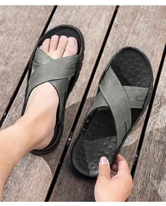 Detailopname van grijze herenstrandsandalen van rundleer met kruisbandontwerp.