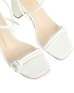 Detailed close-up of white square toe sandals with transparent strap and chunky heel
