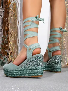 Close-up of green wedge sandals with rhinestone embellishments and lace-up straps.