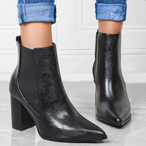 Close-up view of elegant black pointed-toe block heel Chelsea boots with snakeskin texture.