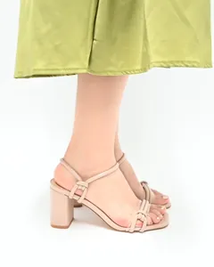 Detailed side view of nude strappy block heel sandals with elegant knot design on a model.