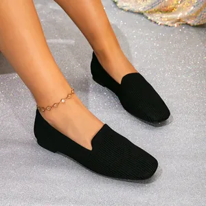 Close-up van stijlvolle zwarte ademende fly-knit loafers op glitter achtergrond.