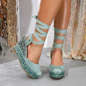 Close-up of green rhinestone wedge sandals with elegant lace-up straps on shimmering floor