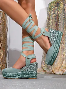 Close-up of mint green lace-up wedge sandals with sparkling rhinestone details
