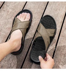 Gedetailleerd aanzicht van bruine leren heren strandsandalen op een houten vlonder