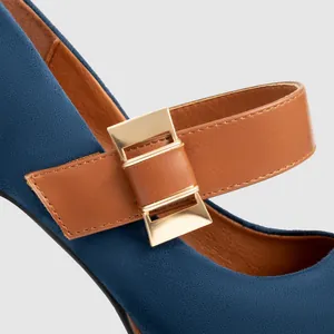 Close-up detail of blue suede Mary Jane shoe featuring brown strap and gold buckle