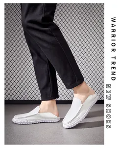 Detailed side view of men's white top-grain leather loafers styled with black trousers