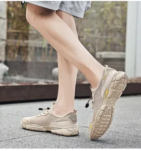 Dichtbij zijaanzicht van beige ademende mesh outdoor sportschoenen voor heren aan de voet