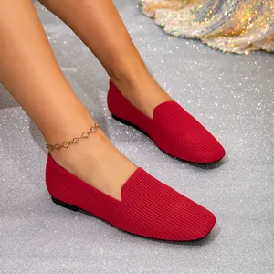 Elegante rode fly-knit instappers voor dames op een zilveren glitterachtergrond.