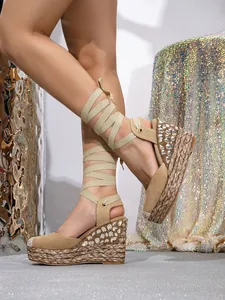 Close-up detail of beige wedge sandals with sparkling rhinestones and elegant lace-up straps