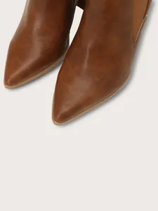 Macro view of the elegant pointed toe on these brown leather-textured winter ankle boots