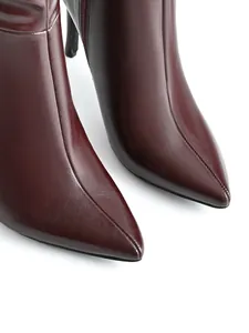 Primo piano di eleganti stivali a spillo bordeaux a punta con trama in morbida pelle.