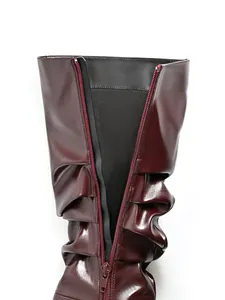 Dettaglio stivali alti bordeaux drappeggiati con zip posteriore e pelle.