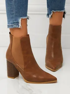 Macro detail of brown pointed toe block heel ankle boots featuring elastic side panels