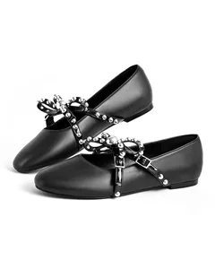Close-up detail of black studded ballet flats with rivet bow and buckled strap.