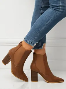 Close-up of brown pointed-toe chunky heel Chelsea boots worn with blue jeans