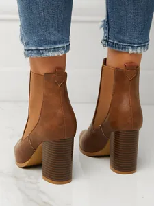 Detail view of stylish brown chunky high heel Chelsea boots with elastic side panels