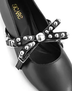 Close-up of black flat shoes featuring silver metal rivets and elegant bow detail