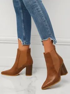 Detail view of tan pointed toe Chelsea boots with a chunky heel and elastic side panel.