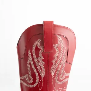 Gros plan de botte de cowboy western en cuir rouge avec broderie blanche et languette