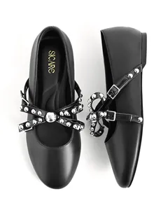 Top-down view of black round-toe flat shoes featuring an ornate studded bow and buckle