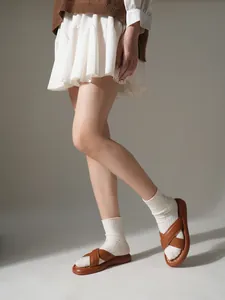 Nahaufnahme von braunen Plateau-Sandalen mit Kreuzriemen, getragen mit weißen Socken.