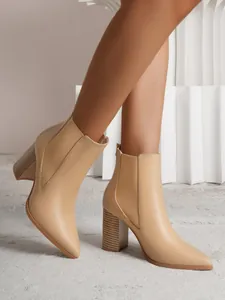 Close-up view of elegant beige pointed toe ankle boots with textured chunky wood grain heel