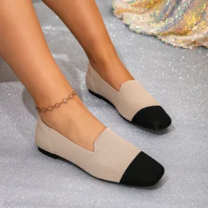 Detail van beige gebreide loafers met contrasterende zwarte neus op modelvoeten.