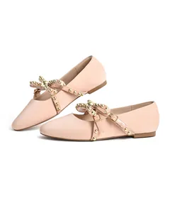 Detailed view of pink ballet flats with studded bow straps and gold-tone buckles.