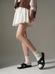 Detailaufnahme schwarzer Plateau-Sandalen mit Kreuzriemen, kombiniert mit weißen Socken.